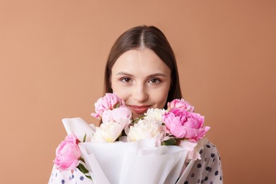 Photo of Woman with beautiful bouquet of peonies on dark beige background