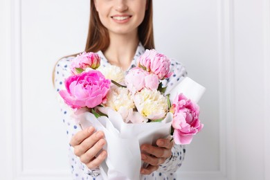 Photo of Woman with beautiful bouquet of peonies near white wall indoors, closeup