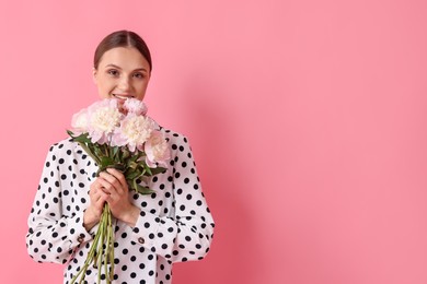 Photo of Woman with beautiful bouquet of peonies on pink background, space for text