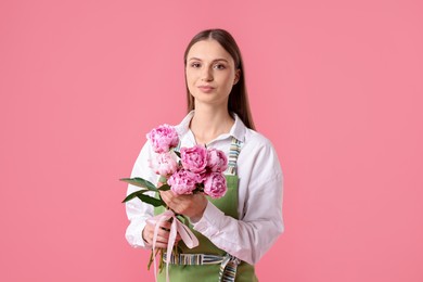 Photo of Florist with beautiful bouquet of peonies on pink background