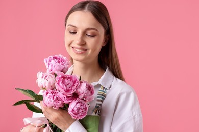 Photo of Florist with beautiful bouquet of peonies on pink background, space for text