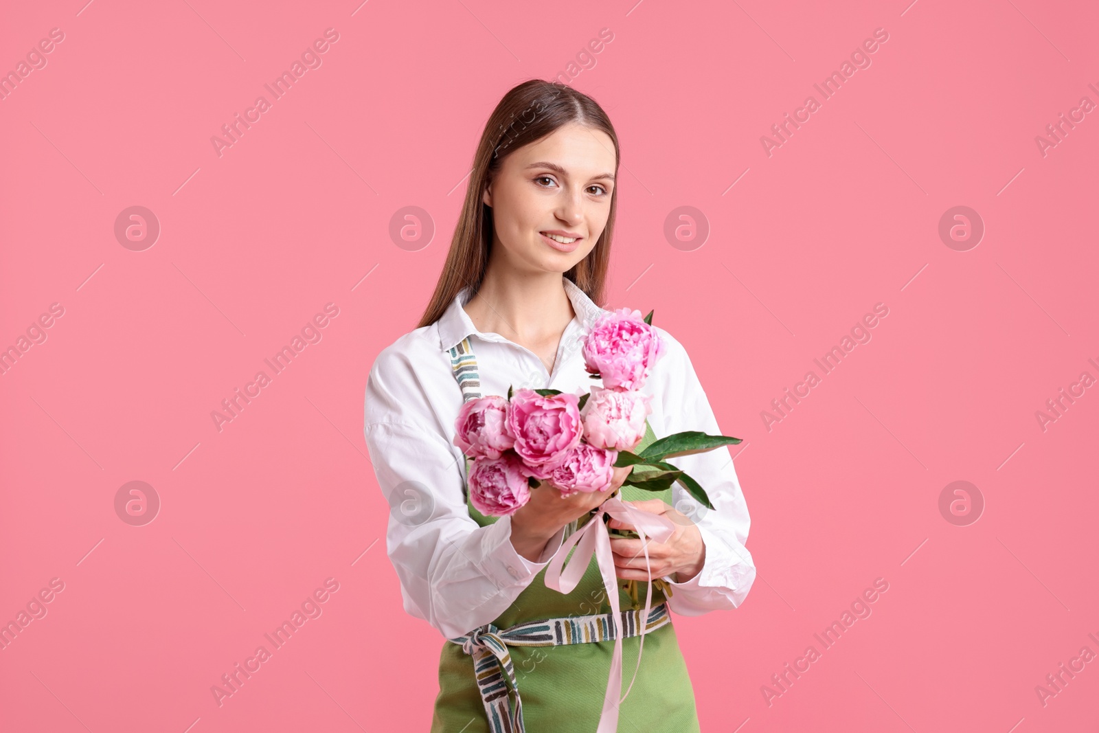 Florist with beautiful bouquet of peonies on pink background Photo of Florist with beautiful bouquet of peonies on pink background