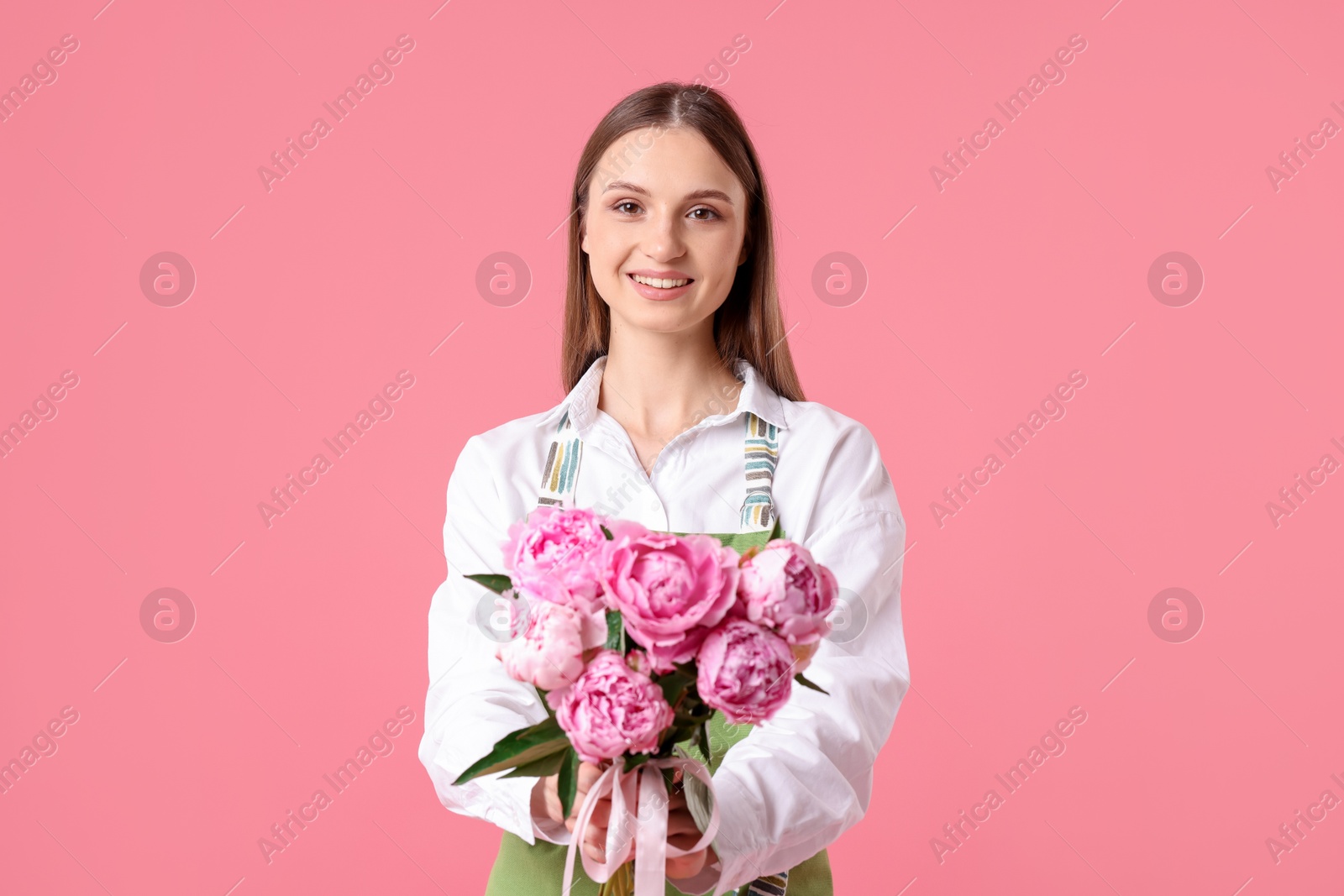 Florist with beautiful bouquet of peonies on pink background Photo of Florist with beautiful bouquet of peonies on pink background