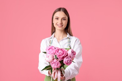 Photo of Florist with beautiful bouquet of peonies on pink background