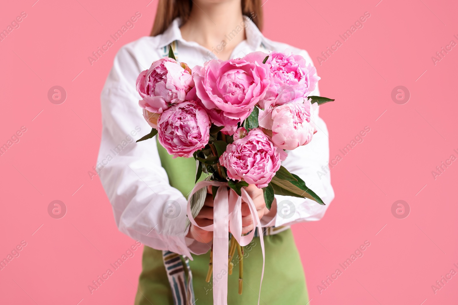Florist with beautiful bouquet of peonies on pink background, closeup Photo of Florist with beautiful bouquet of peonies on pink background, closeup