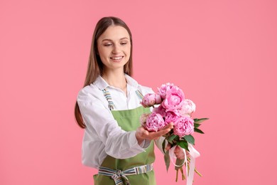 Photo of Florist with beautiful peonies on pink background