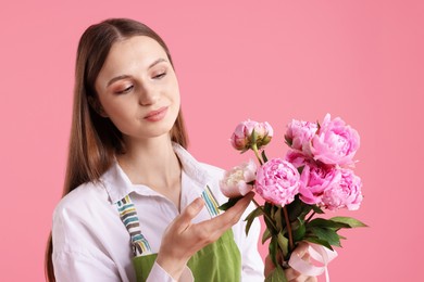 Photo of Florist with beautiful peonies on pink background