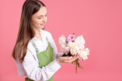 Photo of Florist with beautiful peonies on pink background, space for text