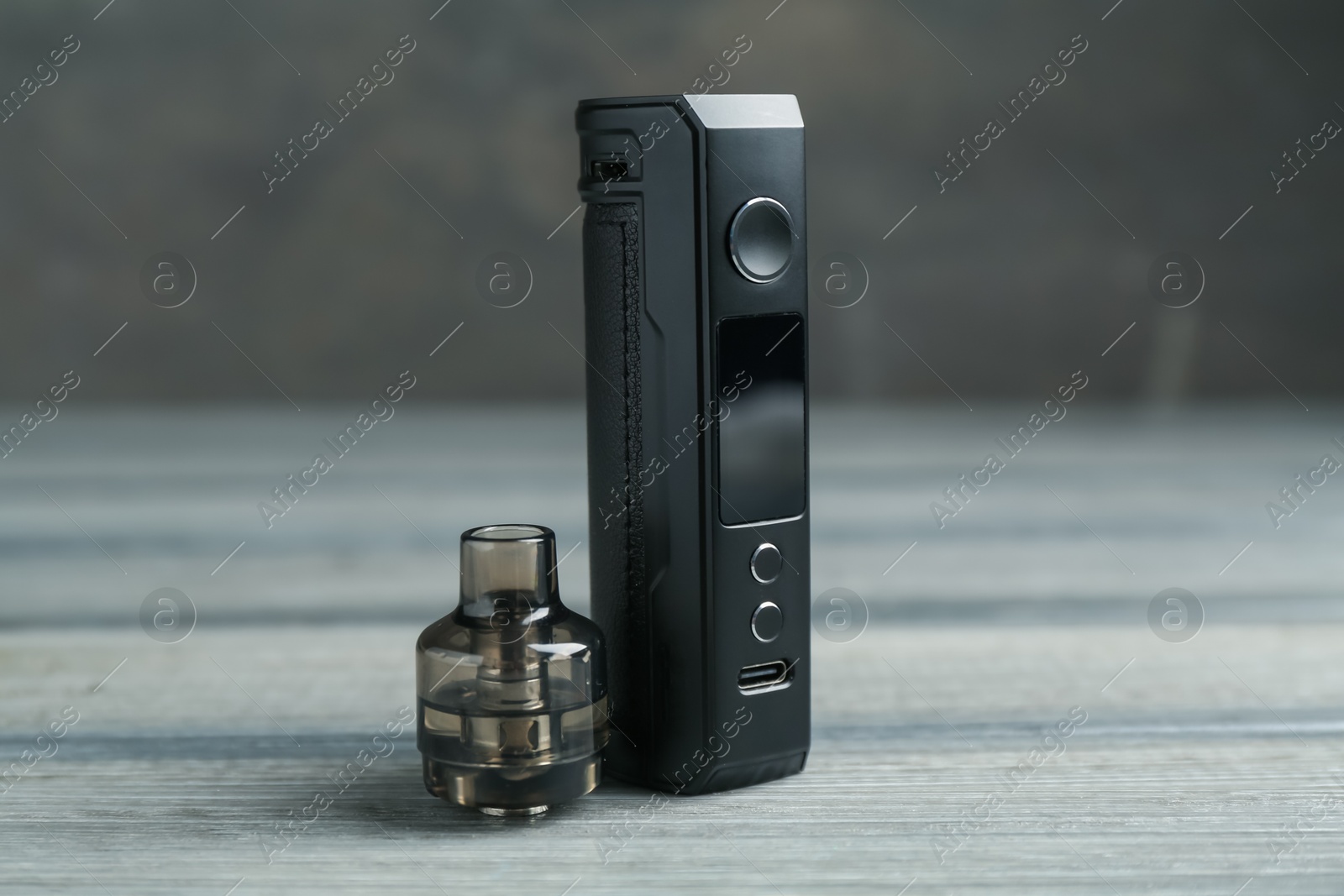 Electronic smoking device and cartridge on wooden table against grey background, closeup Photo of Electronic smoking device and cartridge on wooden table against grey background, closeup