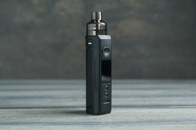 Photo of One electronic smoking device on wooden table against grey background, closeup