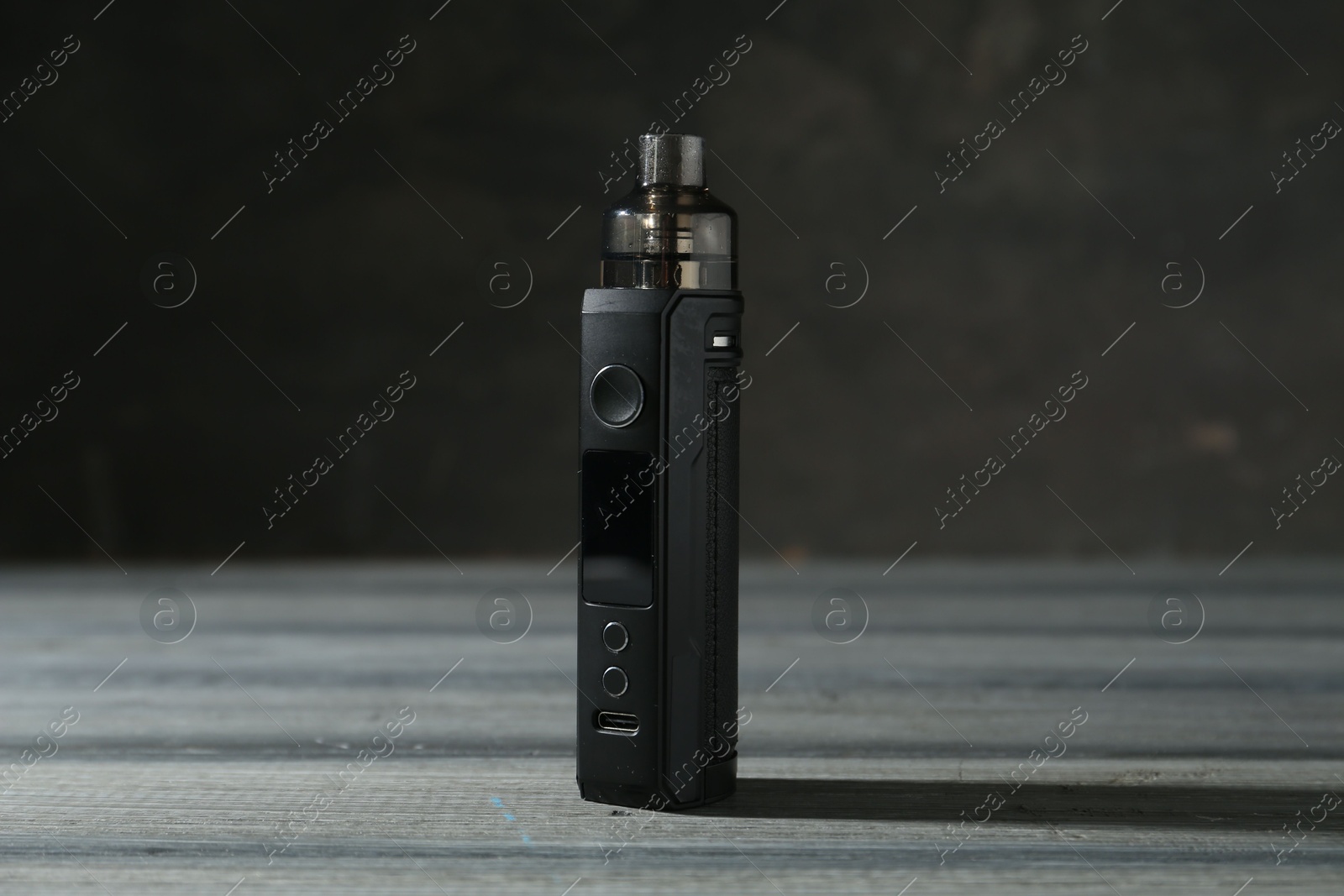 One electronic smoking device on grey wooden table against dark background, closeup Photo of One electronic smoking device on grey wooden table against dark background, closeup