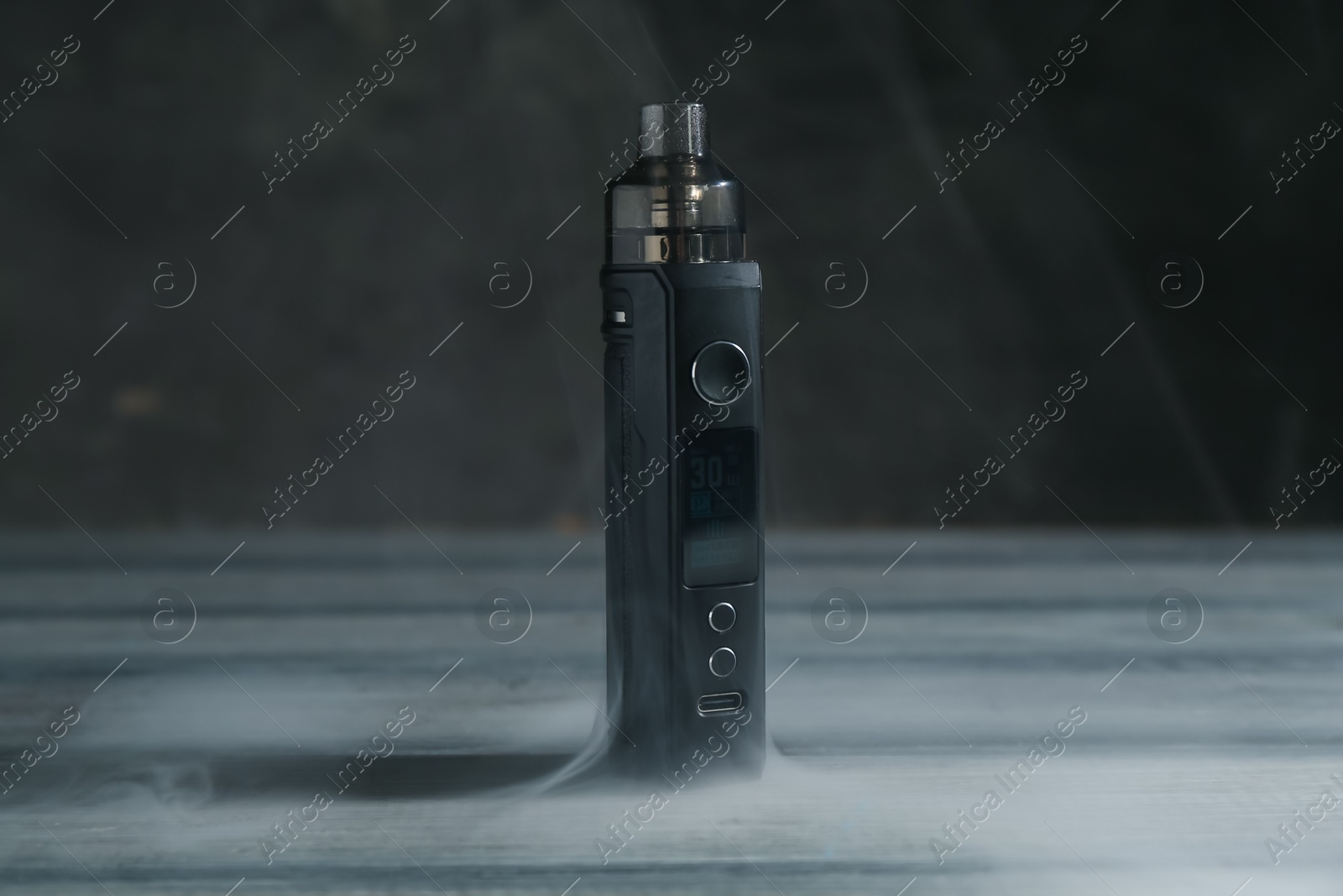 One electronic smoking device in smoke on grey wooden table against dark background, closeup Photo of One electronic smoking device in smoke on grey wooden table against dark background, closeup