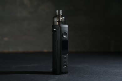 Photo of One electronic smoking device on dark table against grey background, closeup