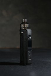 Photo of One electronic smoking device on dark table against grey background, closeup