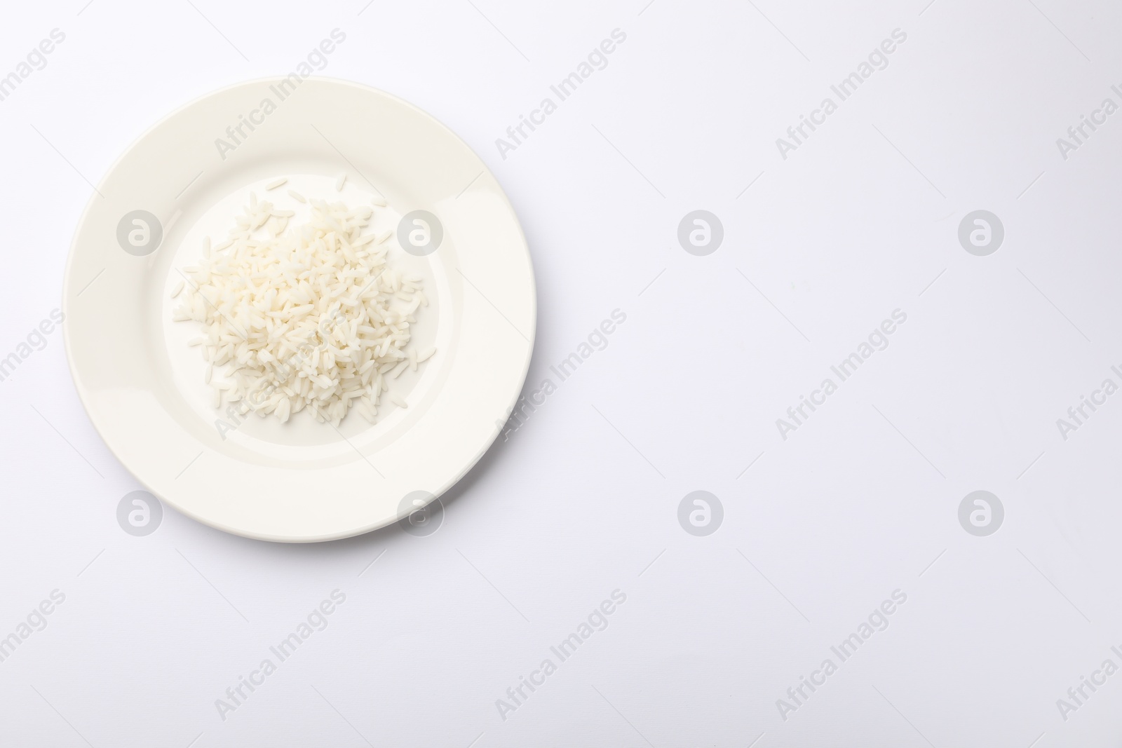 Pile of rice and plate on white table, top view. Space for text Photo of Pile of rice and plate on white table, top view. Space for text