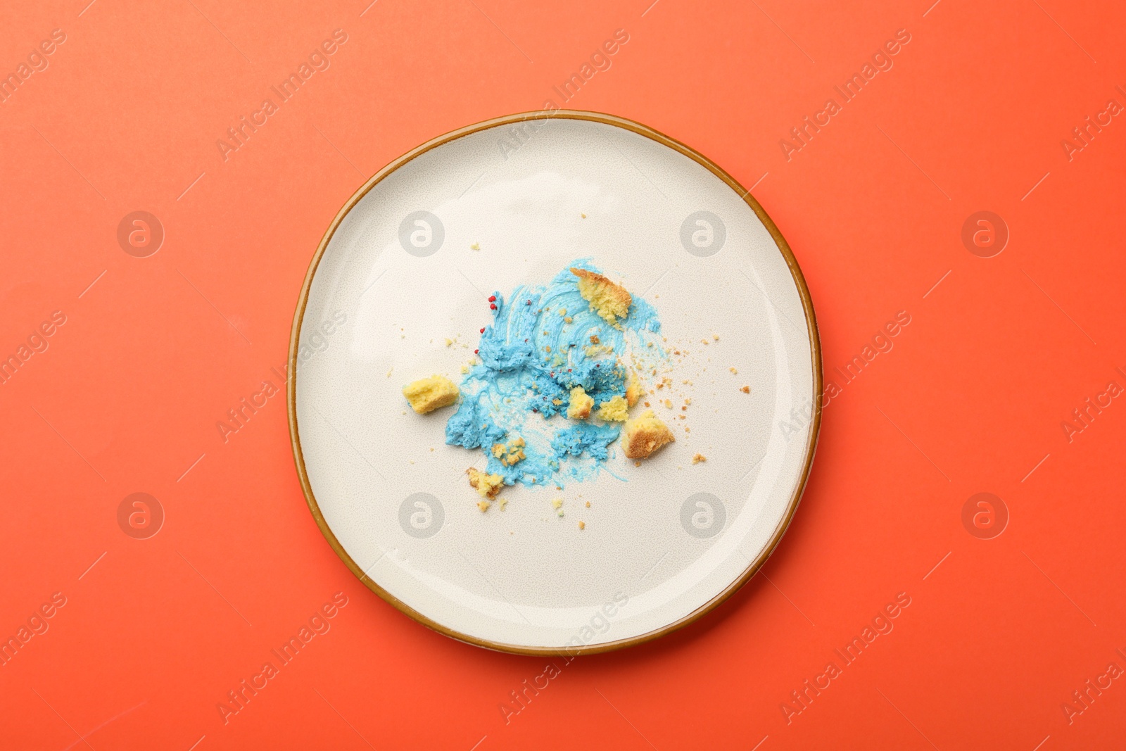 Dirty plate with crumbs and cream on red table, top view Photo of Dirty plate with crumbs and cream on red table, top view