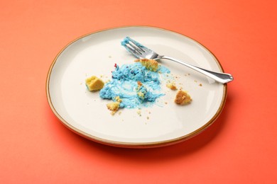 Photo of Dirty plate with crumbs, cream and fork on red table, closeup