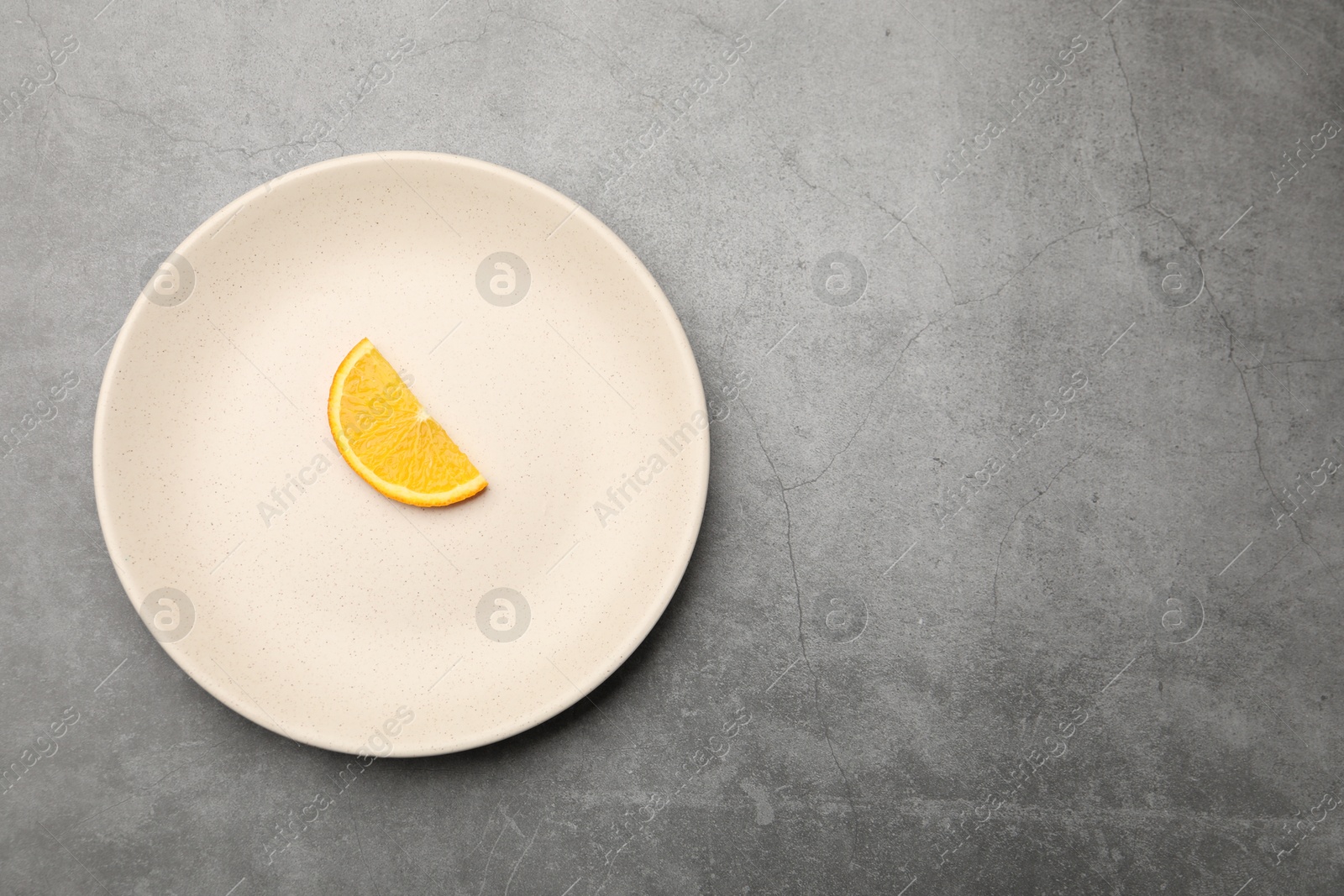 Slice of orange and plate on grey textured table, top view. Space for text Photo of Slice of orange and plate on grey textured table, top view. Space for text