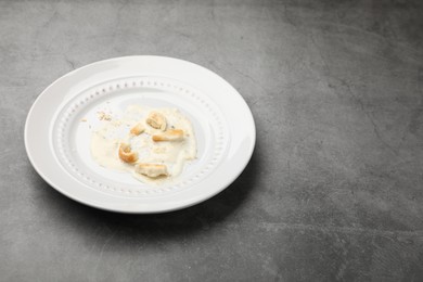 Photo of Dirty plate with crumbs and sauce on grey textured table, closeup. Space for text