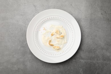 Photo of Dirty plate with crumbs and sauce on grey textured table, top view