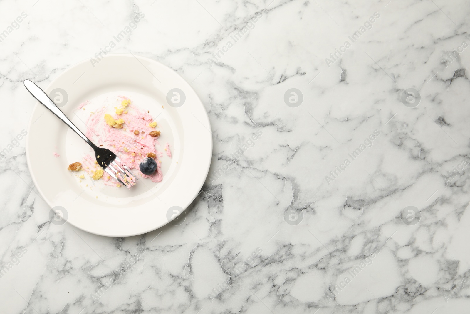 Dirty plate with crumbs, jam, blueberry and fork on white marble table, top view. Space for text Photo of Dirty plate with crumbs, jam, blueberry and fork on white marble table, top view. Space for text