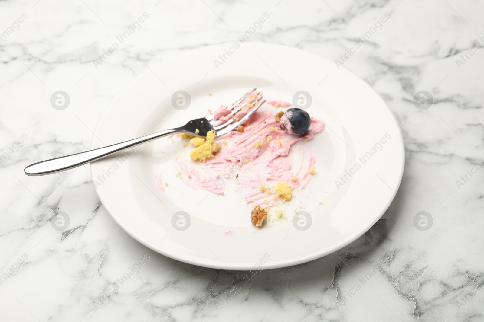Dirty plate with crumbs, jam, blueberry and fork on white marble table, closeup Photo of Dirty plate with crumbs, jam, blueberry and fork on white marble table, closeup