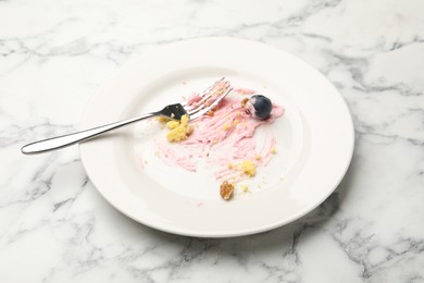 Photo of Dirty plate with crumbs, jam, blueberry and fork on white marble table, closeup