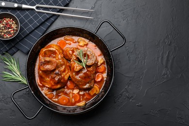 Photo of Tasty beef ossobuco with carrot and mushrooms served on dark textured table, flat lay. Space for text