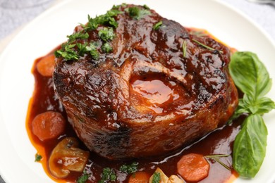 Photo of Tasty beef ossobuco with carrot, mushrooms and herbs on table, closeup