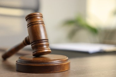 Photo of Judge's gavel on wooden table in office, closeup. Space for text