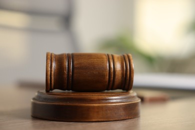 Photo of Judge's gavel on wooden table in office, closeup