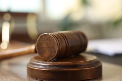 Photo of Judge's gavel on wooden table in office, closeup