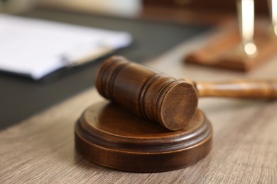 Photo of Judge's gavel on wooden table in office, closeup