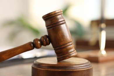 Photo of Judge's gavel on wooden table in office, closeup