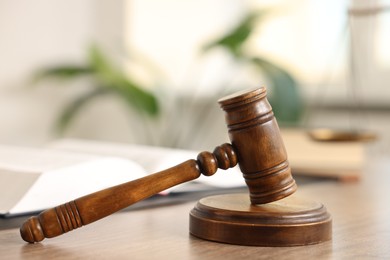 Photo of Judge's gavel on wooden table in office, closeup