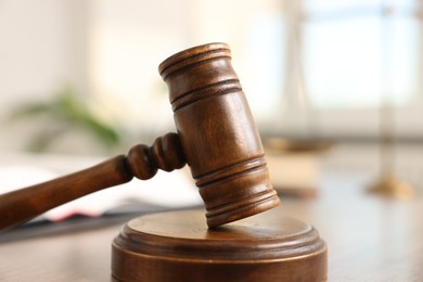 Photo of Judge's gavel on wooden table in office, closeup