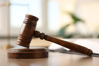 Photo of Judge's gavel on wooden table in office, closeup