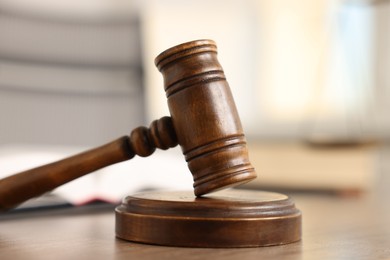 Photo of Judge's gavel on wooden table in office, closeup