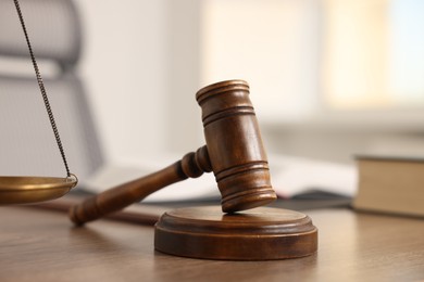 Photo of Judge's gavel on wooden table in office, closeup