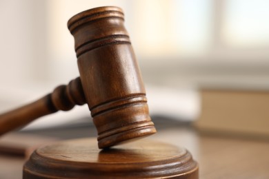 Photo of Judge's gavel on wooden table in office, closeup. Space for text