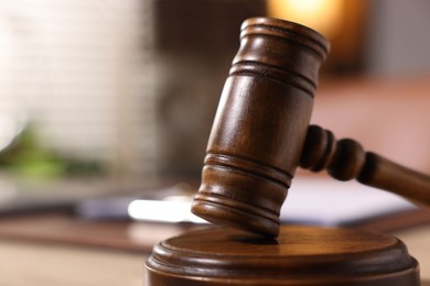 Photo of Judge's gavel on wooden table in office, closeup