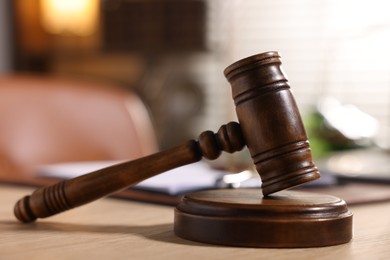 Photo of Judge's gavel on wooden table in office, closeup