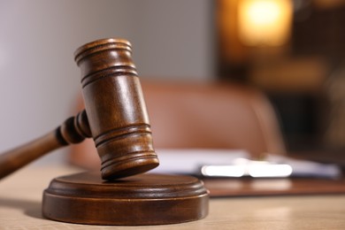 Photo of Judge's gavel on wooden table in office, closeup