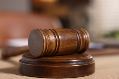 Photo of Judge's gavel on wooden table in office, closeup
