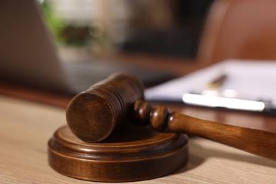 Photo of Judge's gavel on wooden table in office, closeup