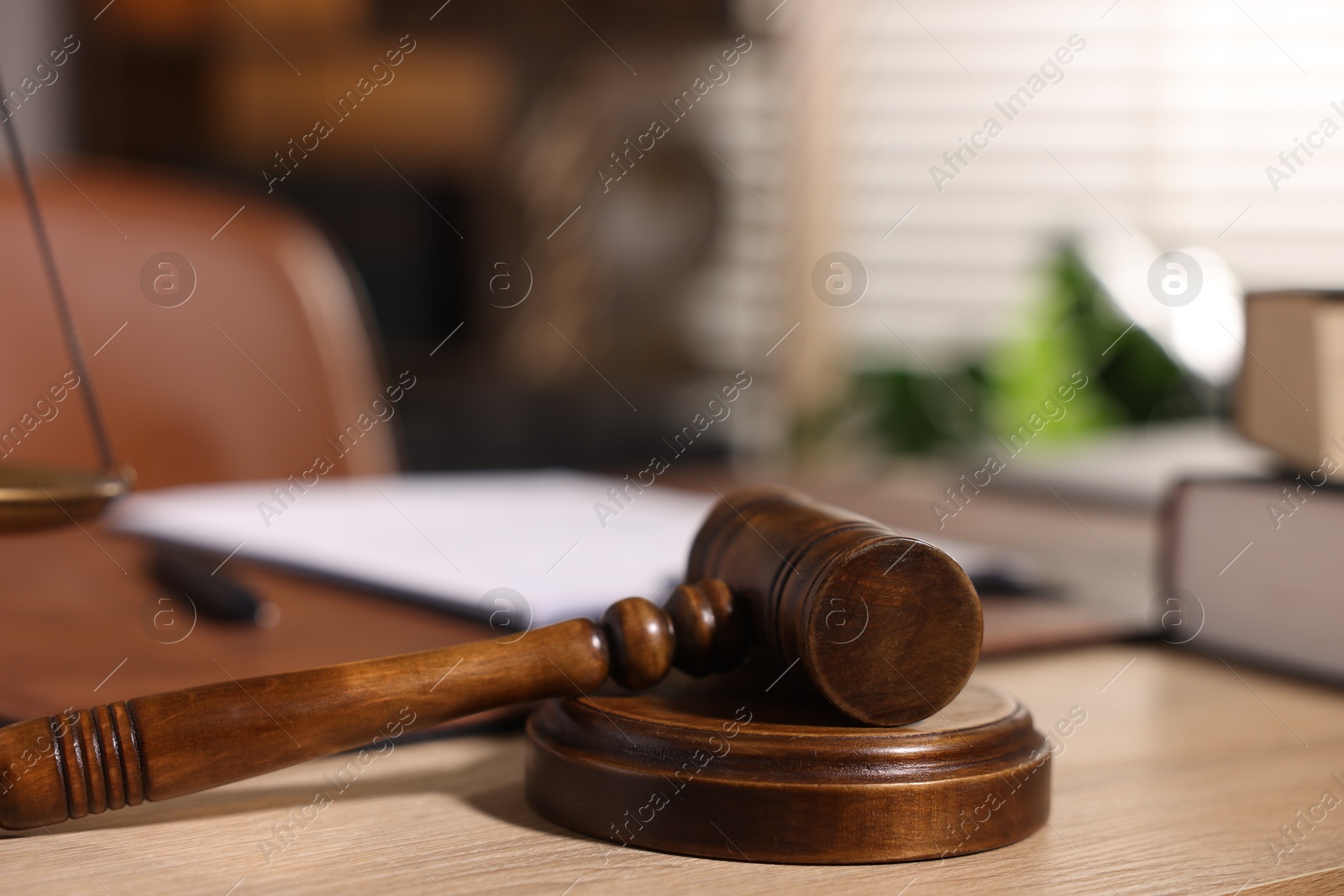 Photo of Judge's gavel on wooden table in office, closeup
