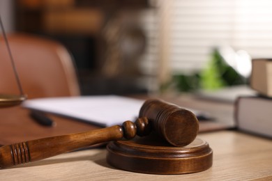 Photo of Judge's gavel on wooden table in office, closeup