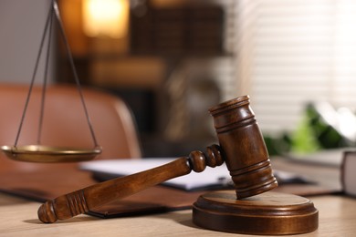 Photo of Judge's gavel on wooden table in office, closeup