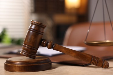 Photo of Judge's gavel on wooden table in office, closeup