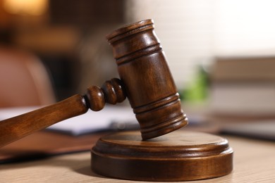Photo of Judge's gavel on wooden table in office, closeup